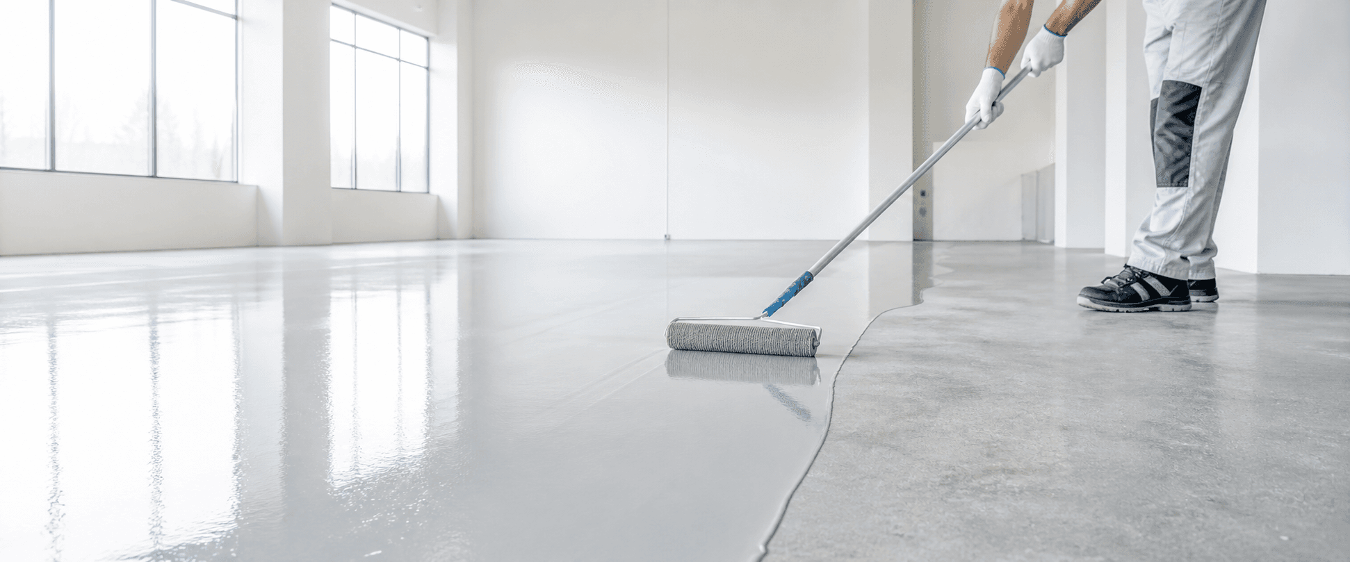 Epoxy floor coating being applied in a bright interior